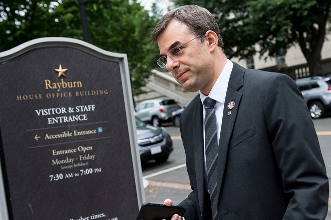 Justin Amash walks outside next to a sign for the Rayburn House Office building